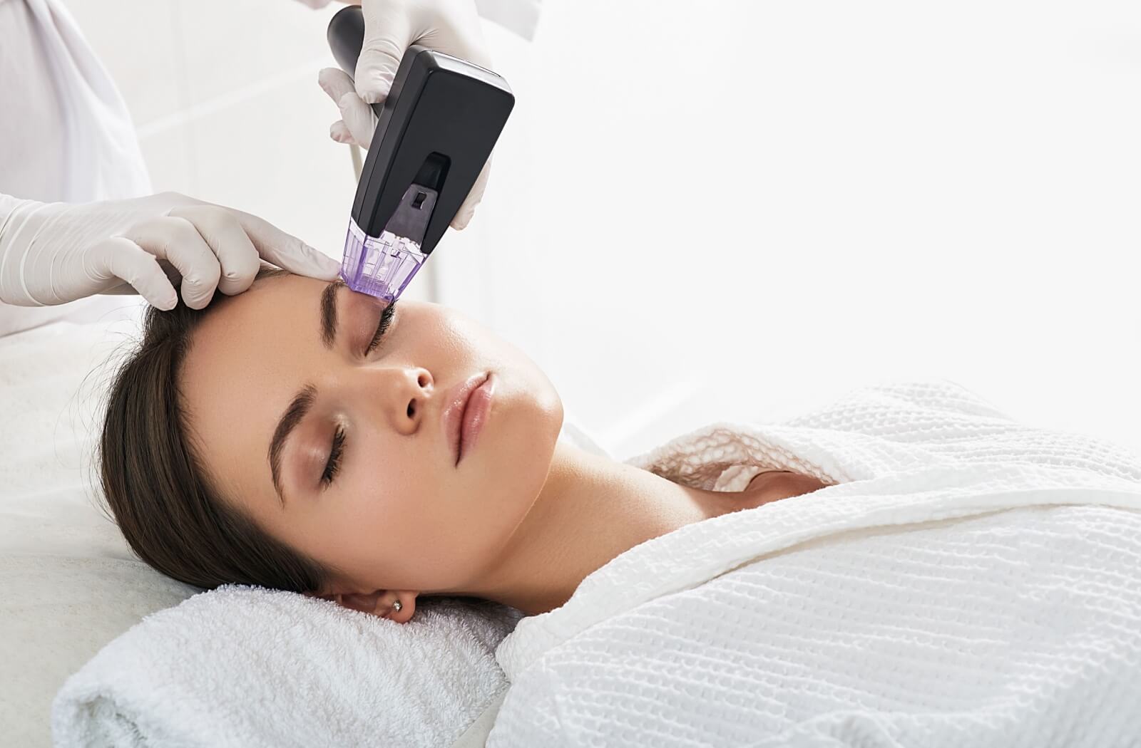 A patient lies back as they undergo a radiofrequency treatment around their eyes.