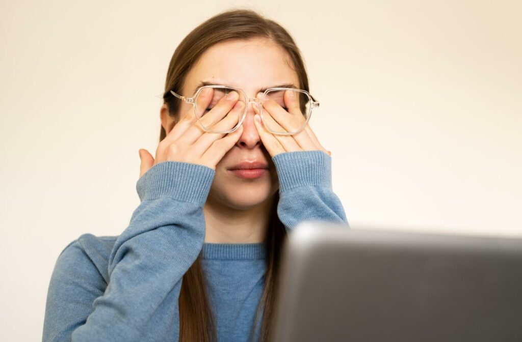 Rubbing eyes in front of a laptop, representing Sjögren's symptoms.